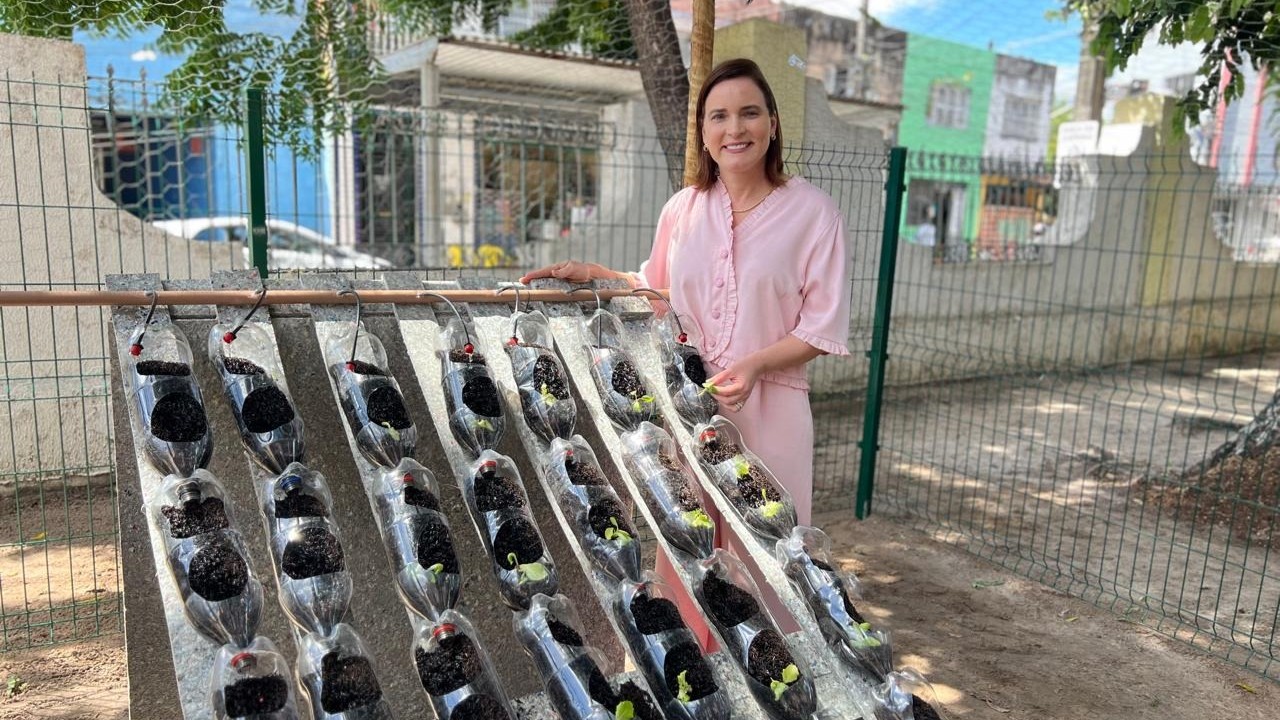 primeira-dama Cristiane Leitão posa para foto ao lado de uma horta hidropônica